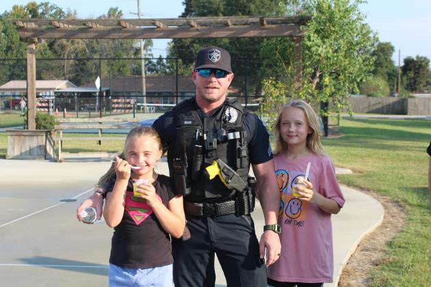 Dayton Police Sgt. Tyler Head (center) visits with Lawren (left) and Autumn Newberry while snacking on ice cream. Article Image Alt Text