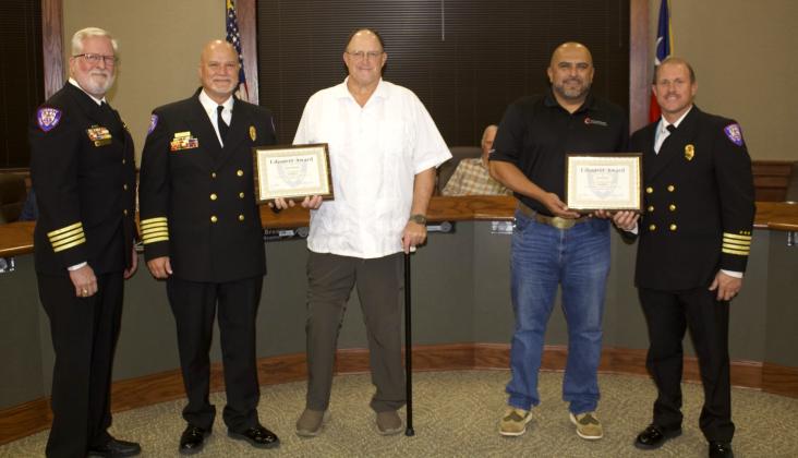 Lindsey Delaney (center) and Bruce Reyes (center right) are given the Lifesaver Award for their efforts in pulling a woman from her burning vehicle. Recognizing the men are Liberty Fire Department Medical Director Dr. Steven Ellerbe, Chief Brian Hurst and Assistant Chief Eric McDaniel. Article Image Alt Text