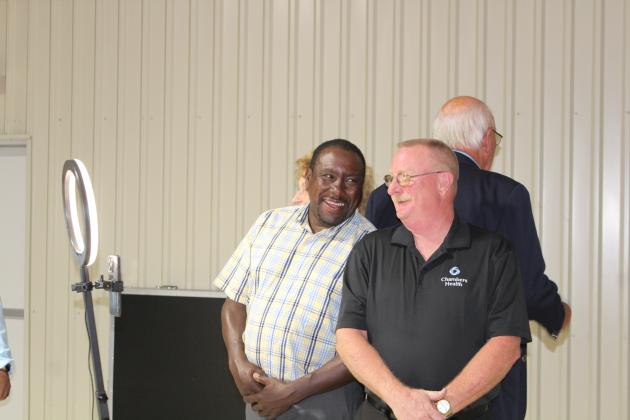 Chambers County Public Hospital District No. 1 Director Eric Humphrey (left) and Chair Andy Legg laugh together while preparing for a photo in a 360 photo booth. Behind them are Directors Annette Abernathy, Linda Tinnerman and Leslie Turner. Article Image Alt Text
